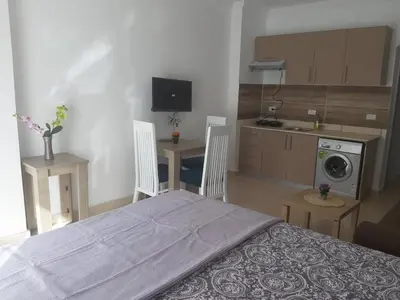 a bedroom with a bed and a table and a kitchen at Exoticky apartman in Hurghada
