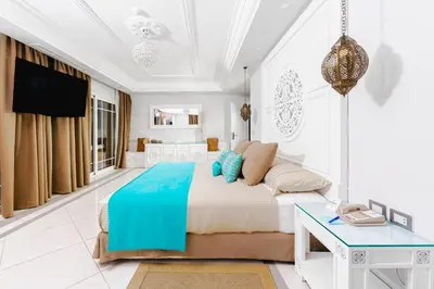 a white bedroom with a large bed and a table at Grand Palace - Couples only 18 years plus in Hurghada