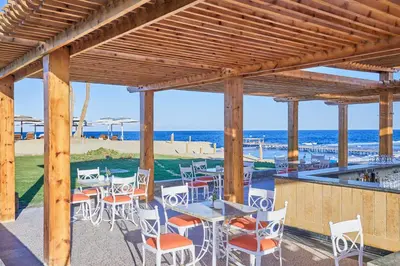 a patio with tables and chairs and the beach at JAZ Neo Reef Marsa in Coraya Bay