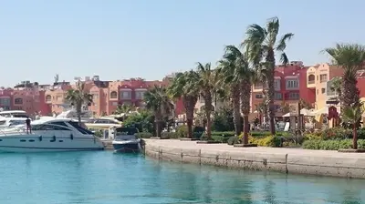 a boat docked in a marina with palm trees and buildings at apartman Eva in Hurghada