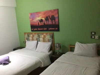 two beds in a room with green walls at Villa Misk in Aswan