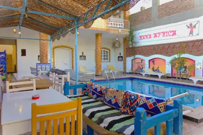 a large swimming pool with a table and chairs at Mama Africa Apts & Studios in Luxor