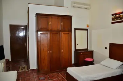 a bedroom with a wooden cabinet and a bed at Dolphin Hotel Safaga in Safaga