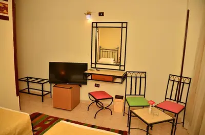 a living room with chairs and a television and a mirror at Dolphin Hotel Safaga in Safaga
