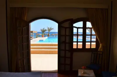 a bedroom with an open door to a swimming pool at Dolphin Hotel Safaga in Safaga