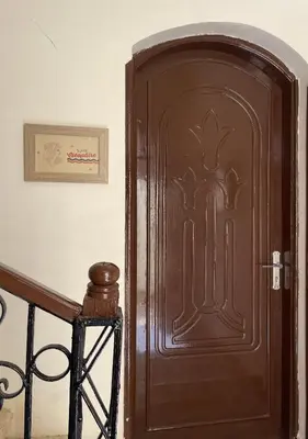 a brown door with a picture on the wall at Gîte Hôtel Ramla Louxor in Luxor