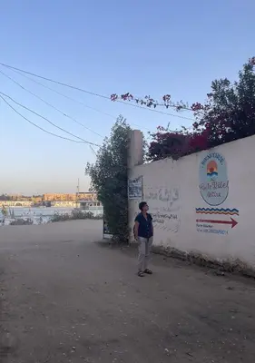 a woman is standing next to a wall at Gîte Hôtel Ramla Louxor in Luxor