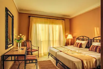 a hotel room with two beds and a table and chairs at JAZ Neo Ivory in Hurghada