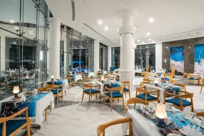 a restaurant with blue tables and chairs and windows at Malikia Resort Abu Dabbab in Abu Dabab