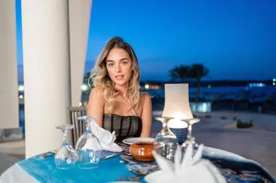 a woman sitting at a table with a table cloth at Malikia Resort Abu Dabbab in Abu Dabab