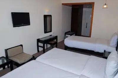 a hotel room with two beds and a chair and a tv at Cleopatra Hotel in Aswan