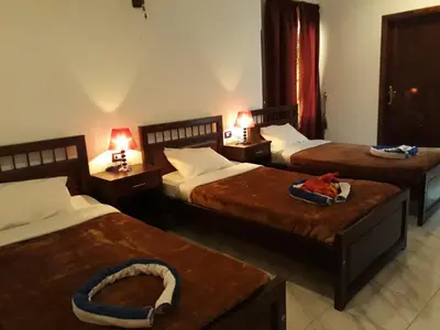 a hotel room with three beds and two tables at Al Hambra Hotel in Luxor