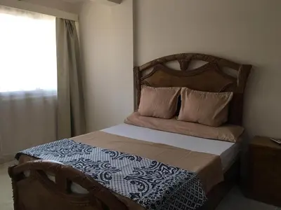 a bedroom with a bed with a wooden headboard and a window at Apartment in Luxor city center-Nil in Luxor