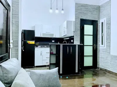 a kitchen with a black refrigerator and white cabinets at Zebra House Hurghada center in Hurghada