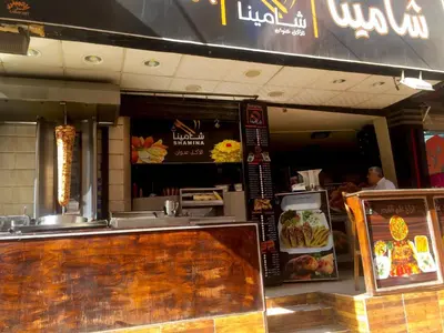 a fast food restaurant with a counter and a person at Zebra House Hurghada center in Hurghada