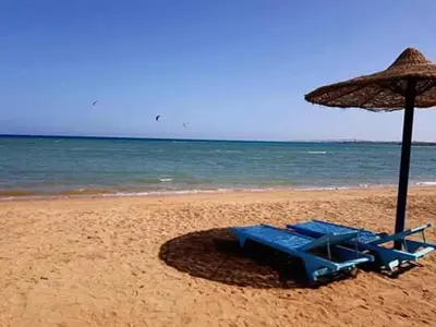 two blue beach chairs and an umbrella on the beach at Chalet in Cecelia Resort in Hurghada