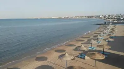 a row of umbrellas and chairs on a beach at Chalet in Cecelia Resort in Hurghada