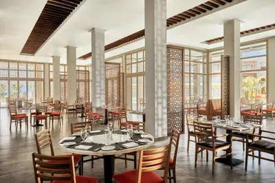 a restaurant with tables and chairs and windows at JAZ Elite Maraya in Coraya Bay