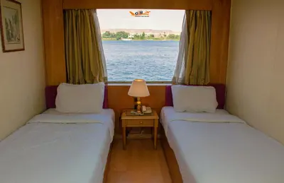 two beds in a small room with a window at Nile Cruise Luxor Aswan 3,4 and 7 nights in Aswan