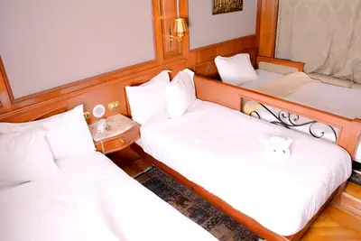 two beds in a room with white sheets at Nile Cruise Luxor Aswan 3,4 and 7 nights in Aswan