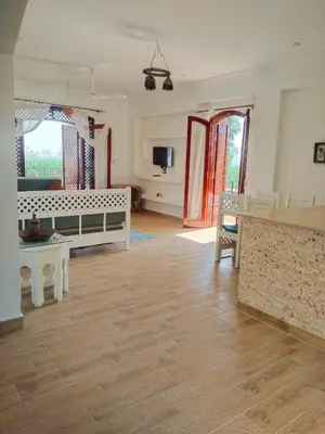 a large living room with wooden floors and a room with a table at Villa Quiet Place in Luxor