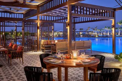 a restaurant with a table and chairs and a pool at Steigenberger Resort Alaya Marsa Alam - Red Sea - Adults Friendly 16 Years Plus in Coraya Bay
