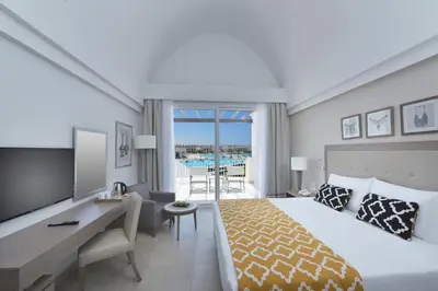 a hotel room with a bed and a desk and a balcony at Steigenberger Resort Alaya Marsa Alam - Red Sea - Adults Friendly 16 Years Plus in Coraya Bay