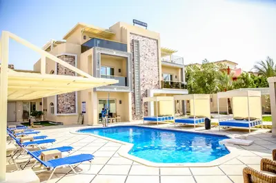 a hotel with a swimming pool and chairs and a building at Serenity Home Hurghada in Hurghada