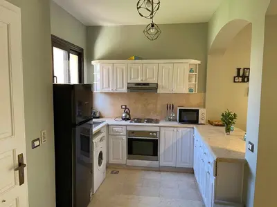 a kitchen with white cabinets and a black refrigerator at El gouna South Marina Townhouse Apartment 3 bedrooms in Hurghada
