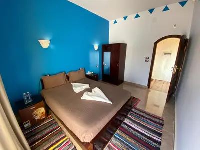 a bedroom with a bed with a blue wall at Kendaka Nubian House in Aswan