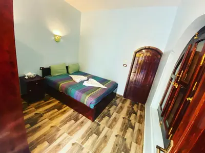 a bedroom with a bed and a wooden floor at Kendaka Nubian House in Aswan
