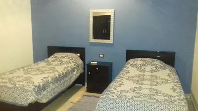 two beds in a bedroom with a blue wall at Villa Bahri Luxor Apartment in Luxor