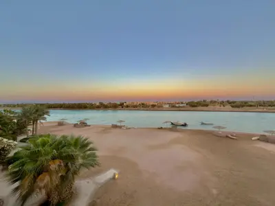 a beach with palm trees and a body of water at Lagoon view 1-bedroom apartment in West Golf El Gouna in Hurghada