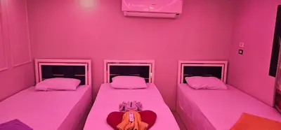 two beds in a room with pink walls at Basmatic Nubian Guest House in Aswan