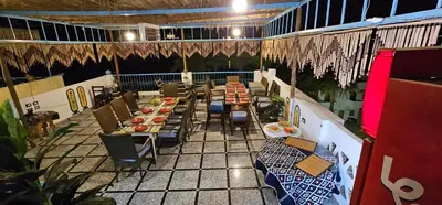 a restaurant with long tables and chairs and aearcherearcherearcher at Basmatic Nubian Guest House in Aswan