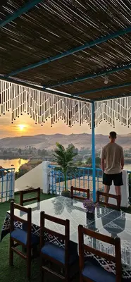 a man standing on a table looking at the sunset at Basmatic Nubian Guest House in Aswan