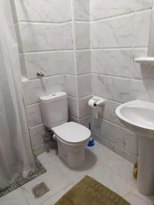 a white bathroom with a toilet and a sink at Studio 5min from ElGouna and Kite station in Hurghada