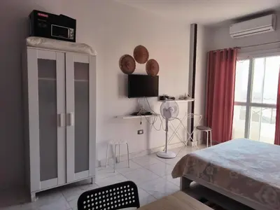 a white room with a bed and a tv and a window at Studio 5min from ElGouna and Kite station in Hurghada