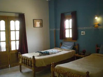a bedroom with two beds and two windows at El Fayrouz Hotel in Luxor