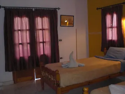 a bedroom with two beds and pink curtains at El Fayrouz Hotel in Luxor