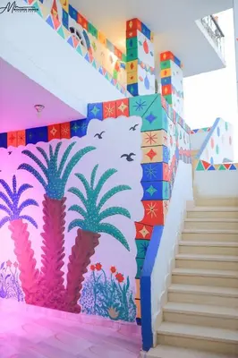 a wall with a mural of palm trees and a staircase at Onaty Ka Guest House in Aswan