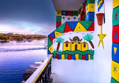 a wall with a painting on it next to the water at Onaty Ka Guest House in Aswan