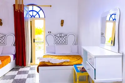 a bedroom with two beds and a mirror at Onaty Ka Guest House in Aswan