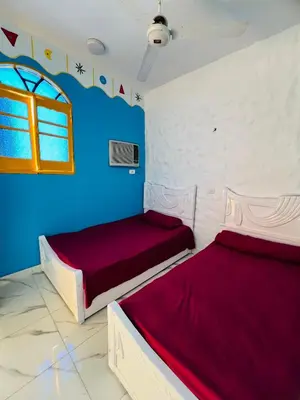 two beds in a room with blue and white walls at Tongel Nubian Studio & Guest House in Aswan