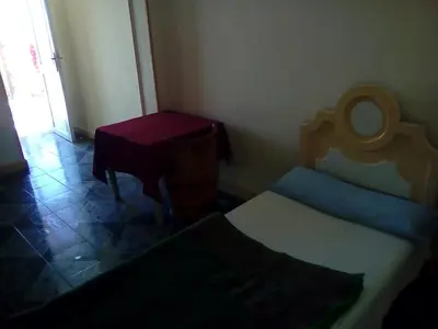 a small room with a bed and a table at Pharaohs Hotel in Luxor