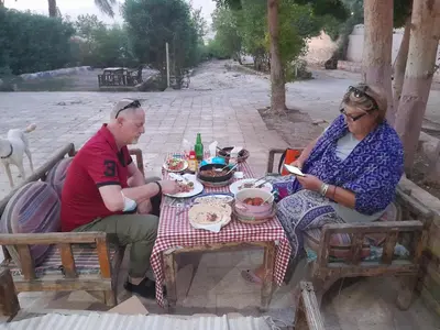 a man and a woman sitting at a table with food at Pharaohs Hotel in Luxor