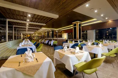 a restaurant with white tables and green chairs at Titanic Royal-Families and Couples only in Hurghada