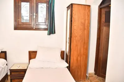 a bedroom with two beds and a wooden cabinet at Om-Abdallah in Aswan