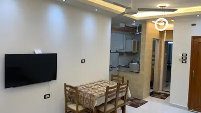 a dining room with a table and a tv on a wall at Roma Apartment ( Center Of Hurghada, Sheraton Road ) in Hurghada