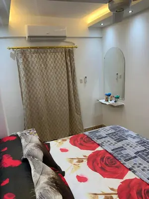 a bedroom with a bed with a floral comforter and a mirror at Roma Apartment ( Center Of Hurghada, Sheraton Road ) in Hurghada